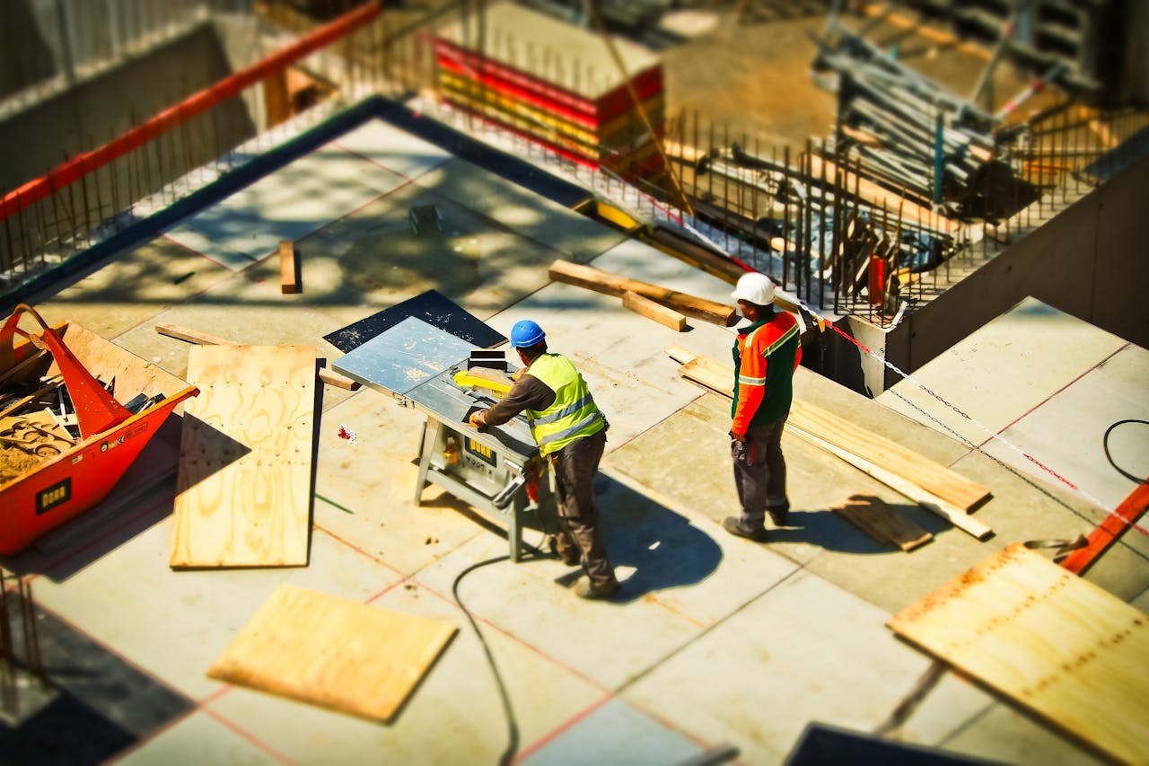 services-03 Construction workers engaging in tasks at an outdoor building site with safety hats and equipment.